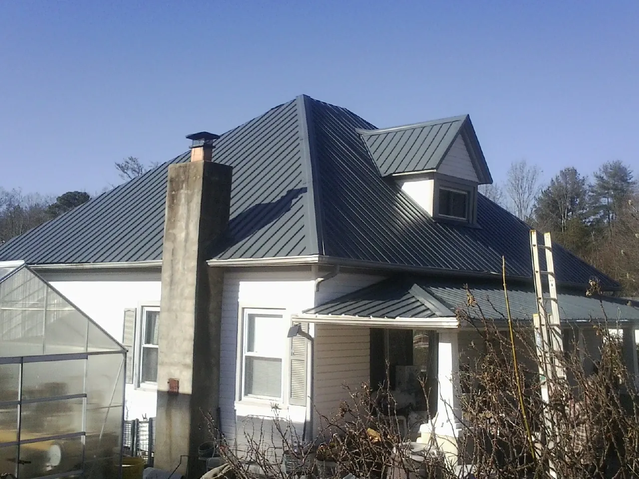 Dark blue standing seam metal roof on a white farmhouse with dormer — Slate & Tile Roof Repair by Roofing Brothers in Landing