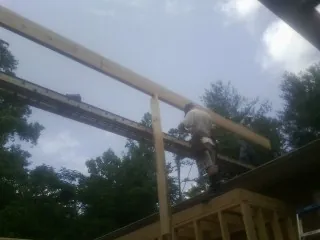 Carpenter setting a ridge beam over a new addition frame — Ice Dam Removal by Roofing Brothers in Landing