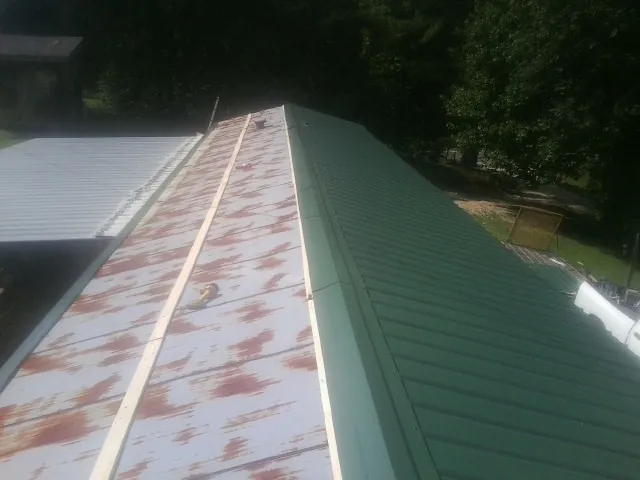 Old rusted panels beside newly installed green metal roofing — Wind Damage Roof Repair by Roofing Brothers in Landing