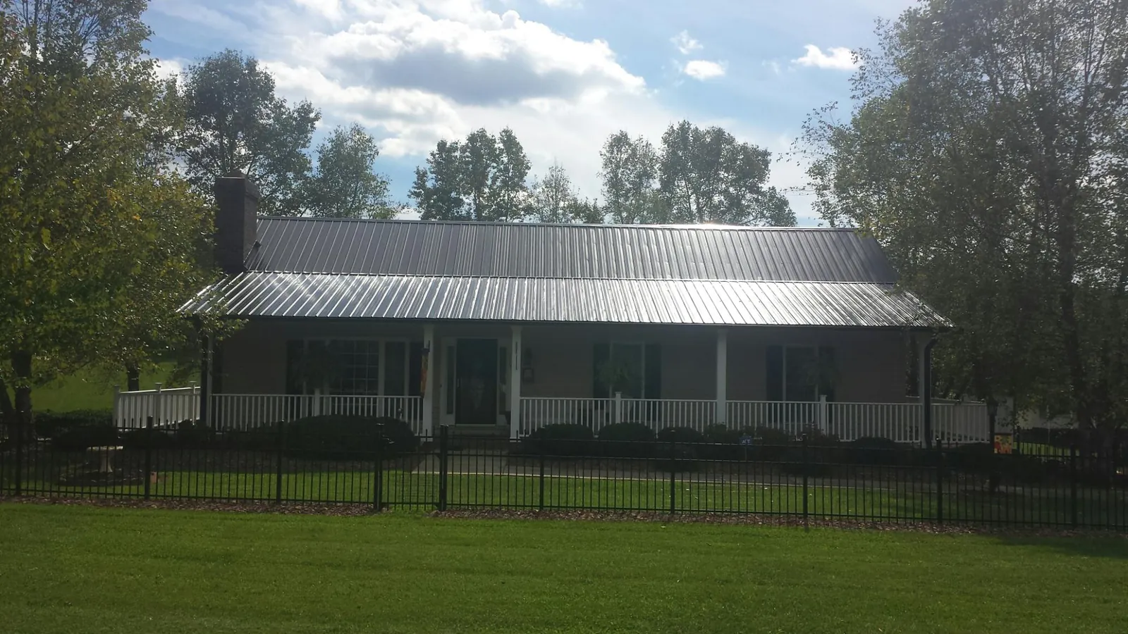 Gray metal roof on a brick ranch with a full width front porch — Gutter Guard Installation work by our crew in Landing