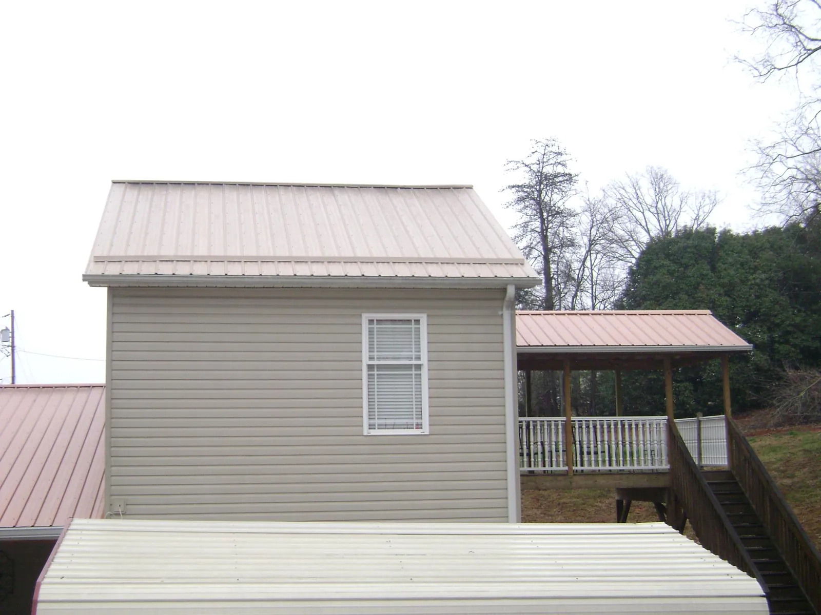 Tan metal roofs on a two story addition and attached porch, from a Roof Replacement job in Landing