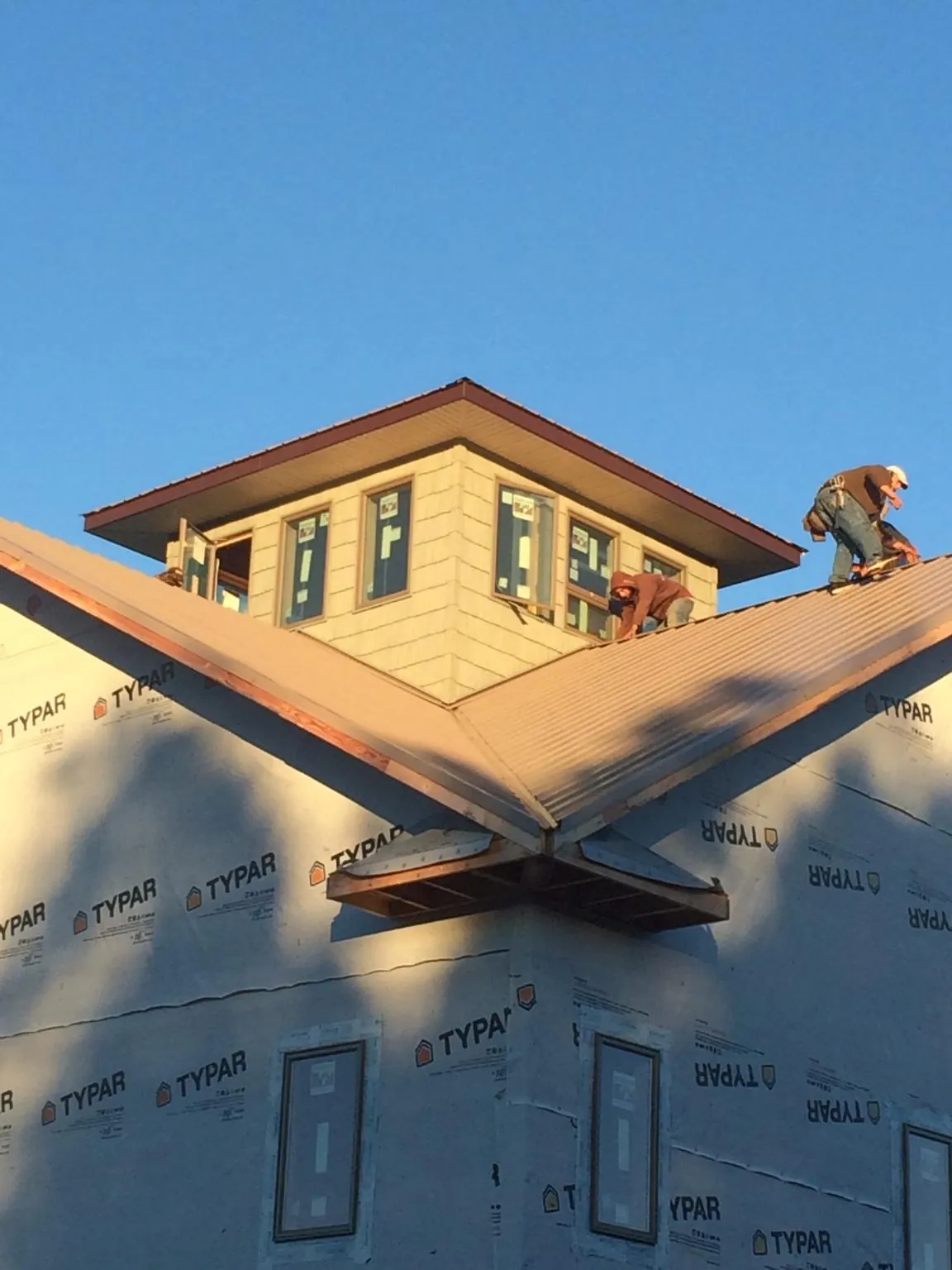 Roofers working around a rooftop cupola on a new metal roof at sunset — Roof Waterproofing in Landing by Roofing Brothers